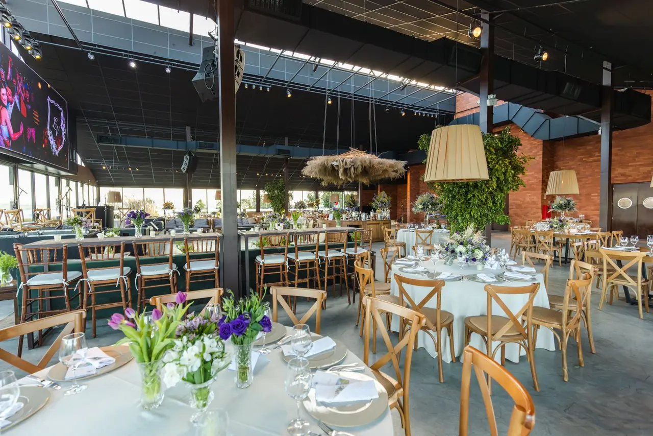 Beautifully decorated indoor wedding reception with elegant table settings and floral arrangements.