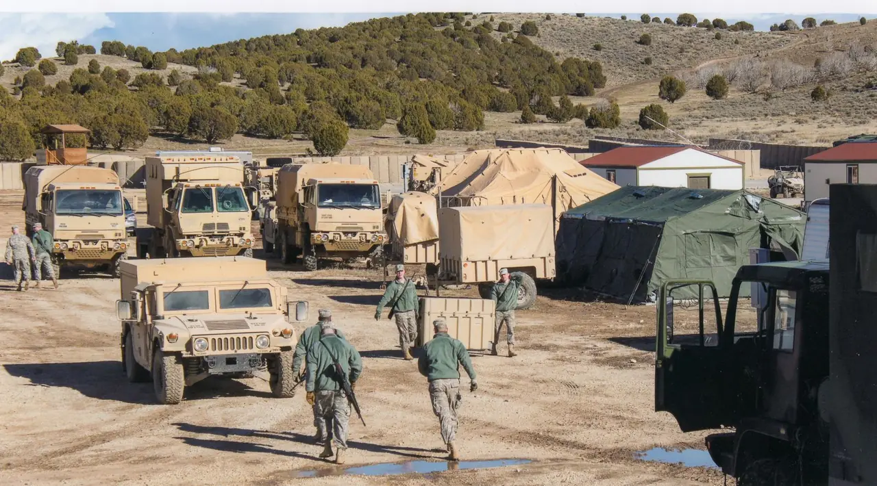 Military vehicles and tents at a training camp in Afghanistan under clear skies.