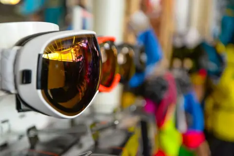 Vibrant ski goggles displayed in a sports store, showcasing reflective lenses and colorful designs.