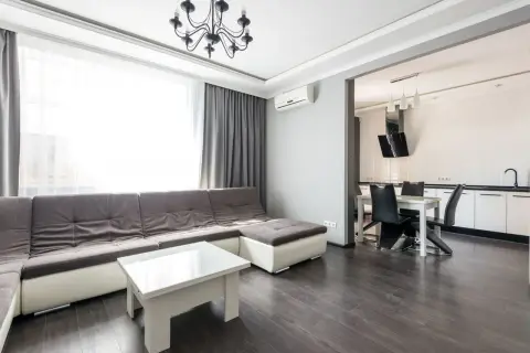 Interior of modern white flat furnished with comfortable couch and dining zone with wooden floor and white wal